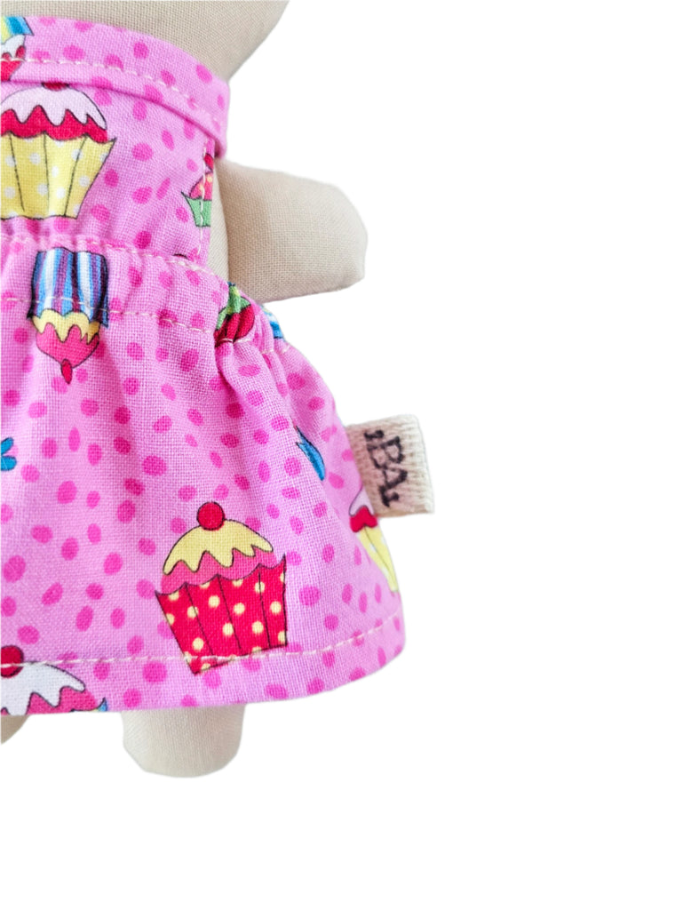 Pink polka dot dress with cupcake design against a white background